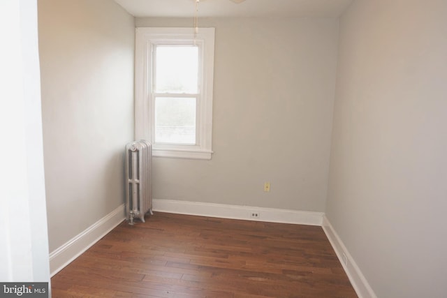 unfurnished room with ceiling fan, radiator, and dark hardwood / wood-style floors