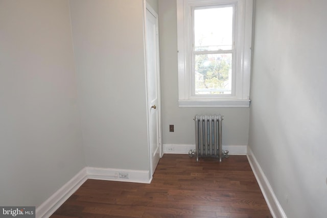 laundry area featuring dark hardwood / wood-style floors, radiator heating unit, and a wealth of natural light