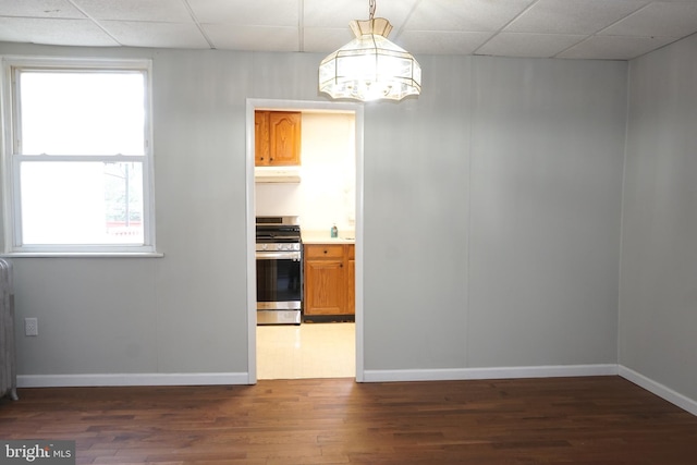 interior space featuring hanging light fixtures, a paneled ceiling, stainless steel range, and dark hardwood / wood-style floors