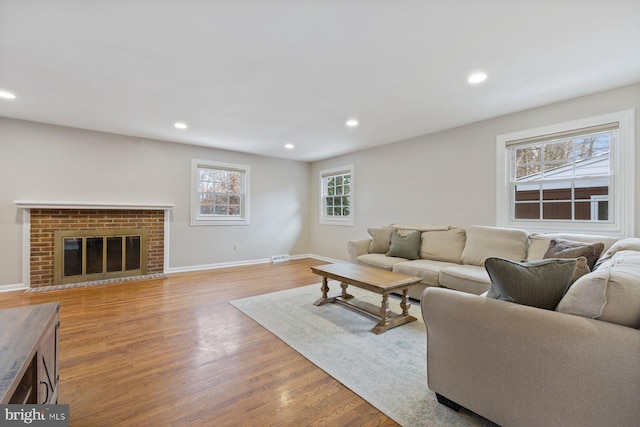 living room featuring a brick fireplace and light wood-type flooring