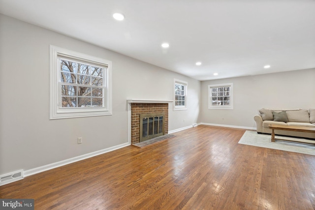 unfurnished living room featuring hardwood / wood-style flooring and a brick fireplace