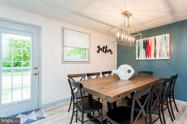 dining room with light wood-style flooring, a chandelier, and baseboards