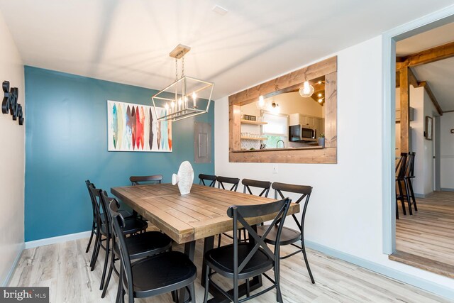 dining room with baseboards, light wood-type flooring, and a notable chandelier