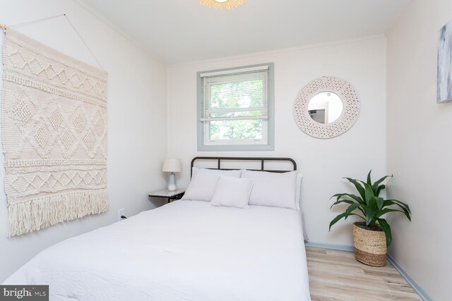 bedroom featuring wood finished floors, crown molding, and baseboards