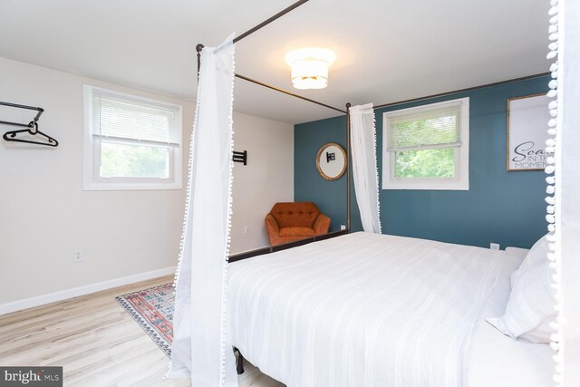 bedroom with wood finished floors, baseboards, and multiple windows