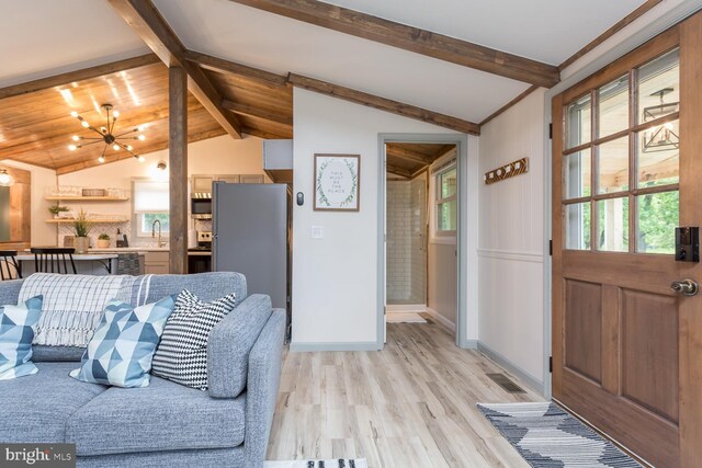 living room featuring lofted ceiling with beams, light wood-style flooring, and baseboards