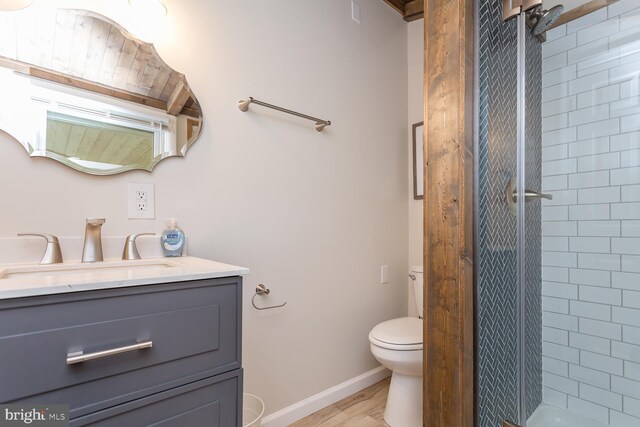 bathroom featuring vanity, toilet, a stall shower, baseboards, and wood finished floors