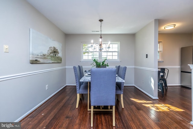 dining area with dark wood-type flooring and a chandelier