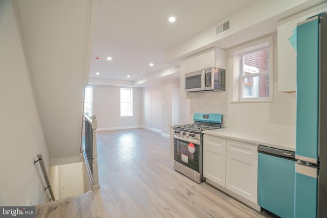 kitchen featuring decorative backsplash, light hardwood / wood-style flooring, white cabinets, and stainless steel appliances