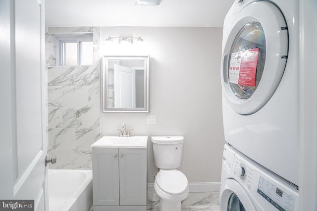 bathroom with vanity, stacked washer / dryer, and toilet