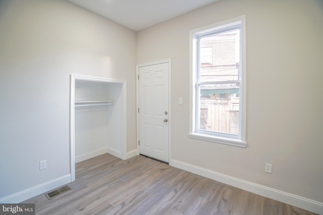 unfurnished bedroom with a closet and light hardwood / wood-style floors