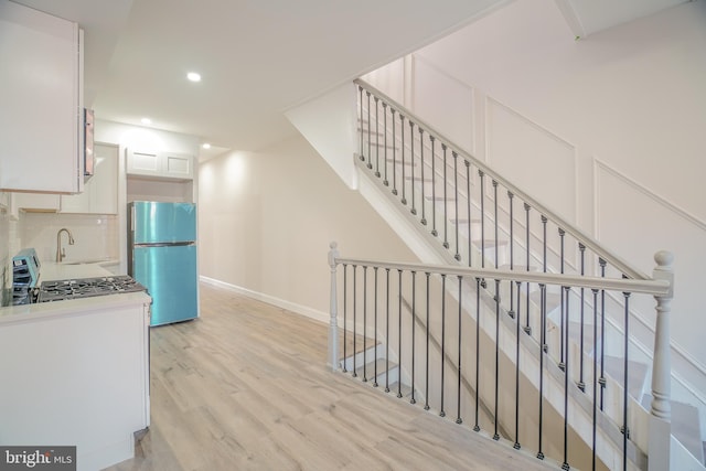 staircase with hardwood / wood-style floors and sink