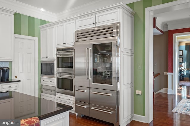 kitchen featuring white cabinets, dark countertops, and double oven
