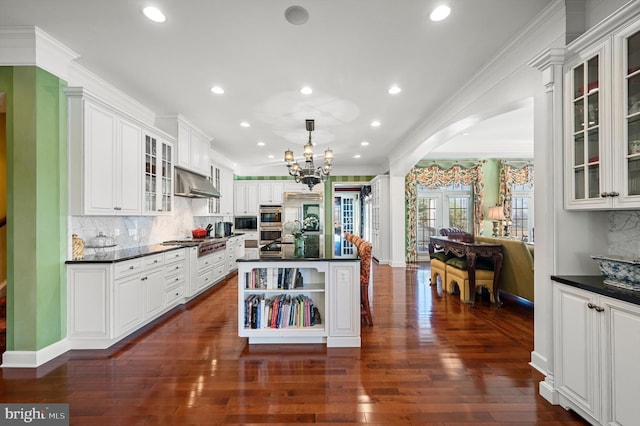kitchen with dark countertops, decorative backsplash, under cabinet range hood, and stainless steel appliances