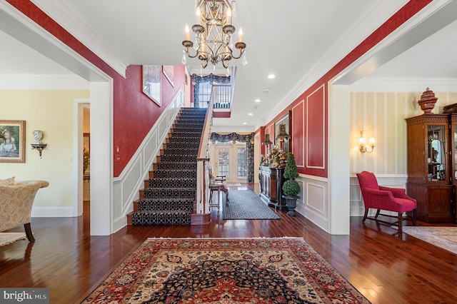 foyer featuring dark wood-type flooring, ornamental molding, and a chandelier