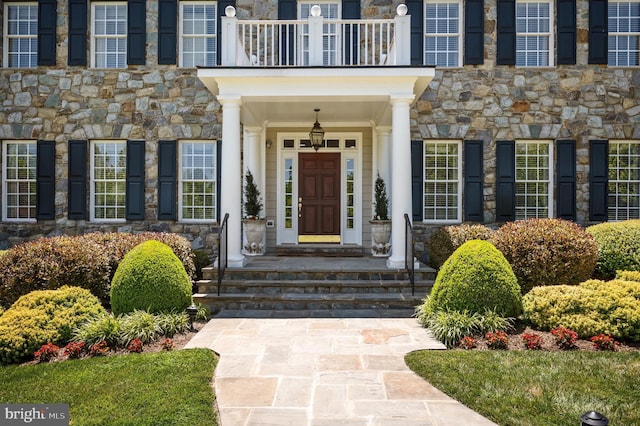 entrance to property featuring stone siding and a balcony