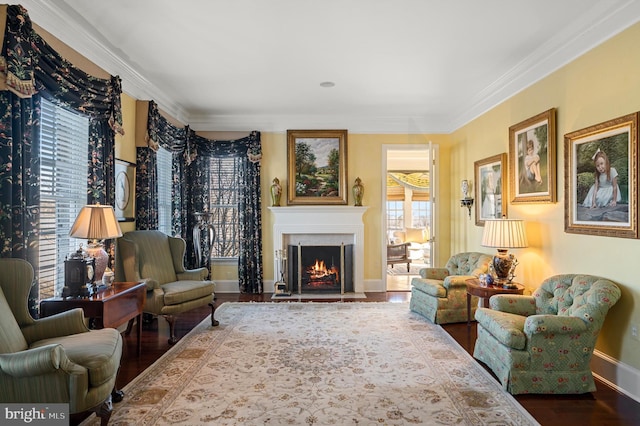 sitting room with a fireplace with flush hearth, baseboards, ornamental molding, and wood finished floors