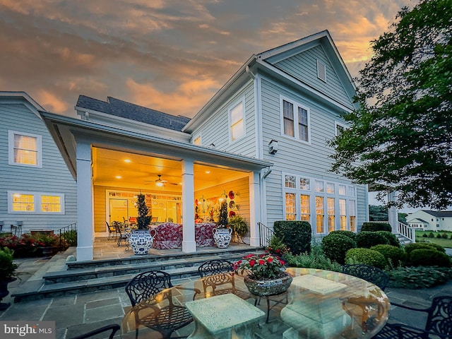 back house at dusk featuring a patio area