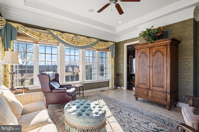 interior space with a ceiling fan, crown molding, light tile patterned flooring, a raised ceiling, and baseboards