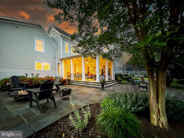 back house at dusk with a patio and an outdoor fire pit