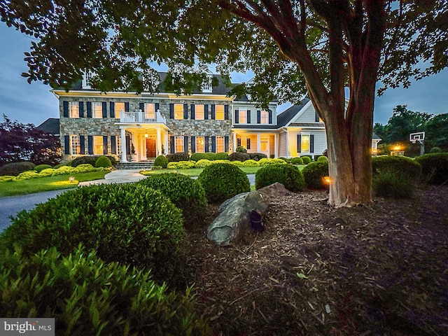 colonial inspired home featuring stone siding and a balcony