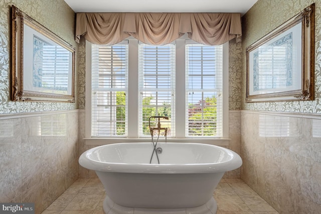 bathroom featuring tile patterned floors, a bath, and tile walls