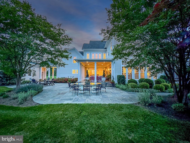 back of property at dusk featuring a yard and a patio