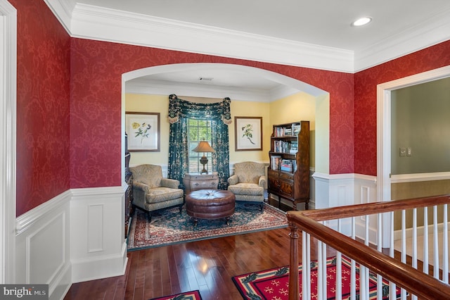 living area with arched walkways, wallpapered walls, and wainscoting