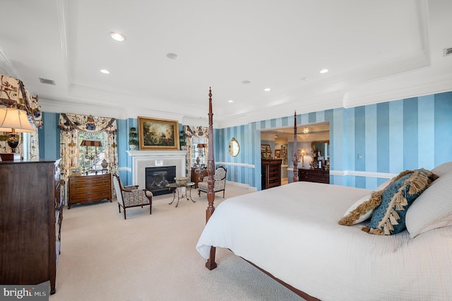 bedroom featuring wallpapered walls, a tray ceiling, ornamental molding, carpet floors, and a glass covered fireplace