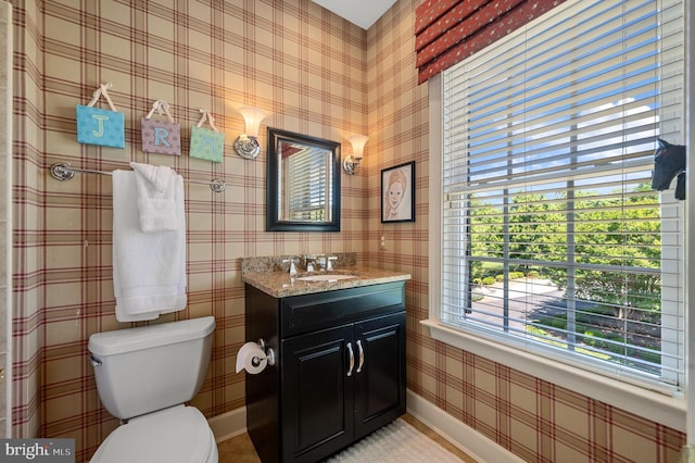 bathroom featuring toilet, vanity, and baseboards