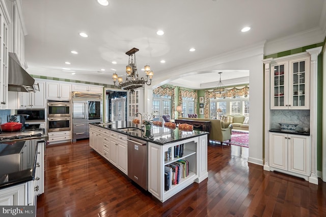 kitchen featuring arched walkways, a sink, a notable chandelier, appliances with stainless steel finishes, and ornamental molding