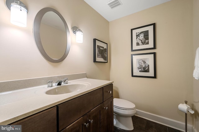 half bathroom featuring tile patterned floors, toilet, baseboards, visible vents, and vanity