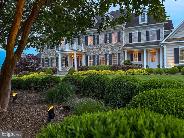 colonial inspired home featuring stone siding and a balcony