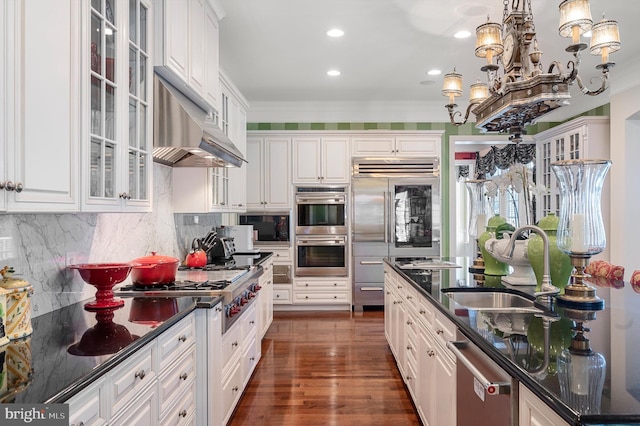 kitchen with built in appliances, sink, hanging light fixtures, and white cabinets