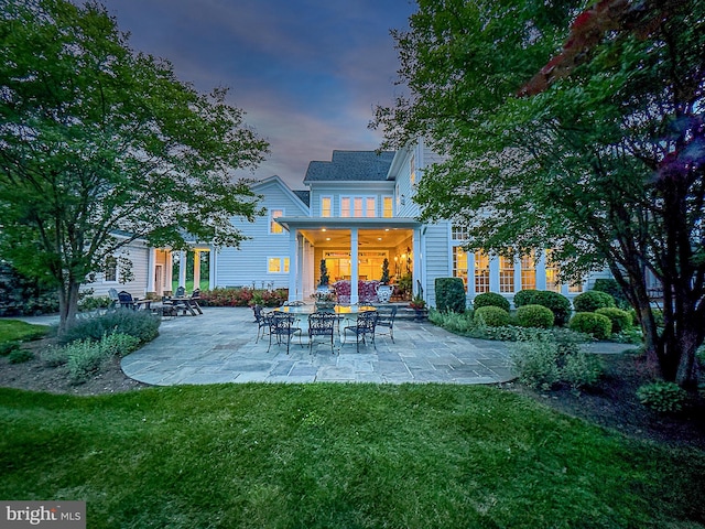 back house at dusk with a yard and a patio area