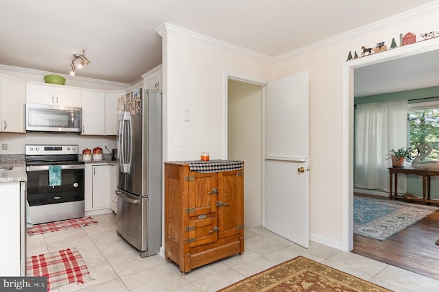 kitchen with appliances with stainless steel finishes, crown molding, white cabinetry, and light hardwood / wood-style flooring