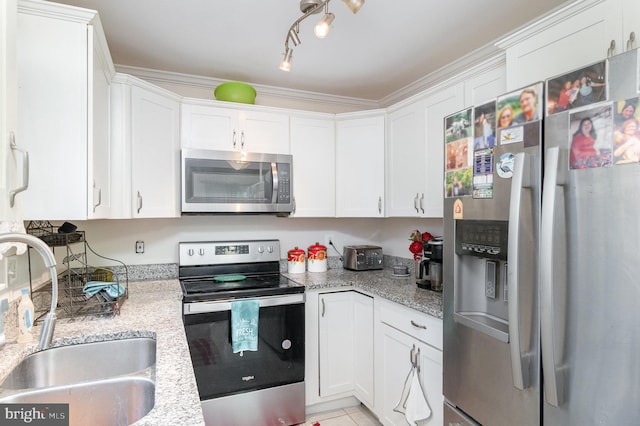 kitchen with light stone countertops, stainless steel appliances, sink, and white cabinetry