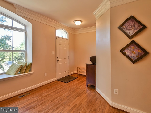 foyer entrance with ornamental molding and light wood-type flooring