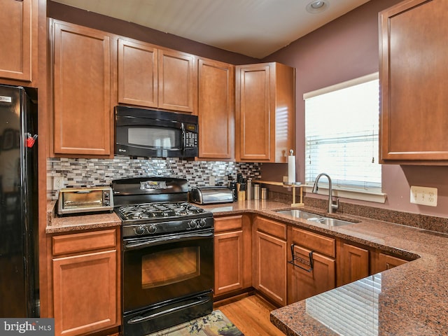 kitchen with backsplash, black appliances, sink, and light hardwood / wood-style flooring