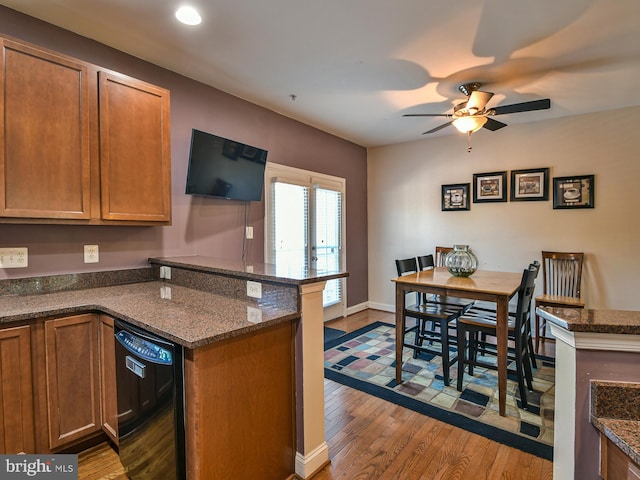 kitchen featuring ceiling fan, wood-type flooring, kitchen peninsula, dark stone counters, and dishwasher