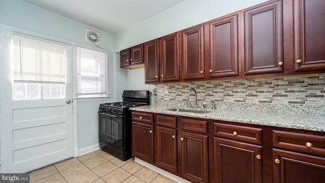 kitchen with tasteful backsplash, sink, black gas stove, light stone counters, and light tile patterned floors