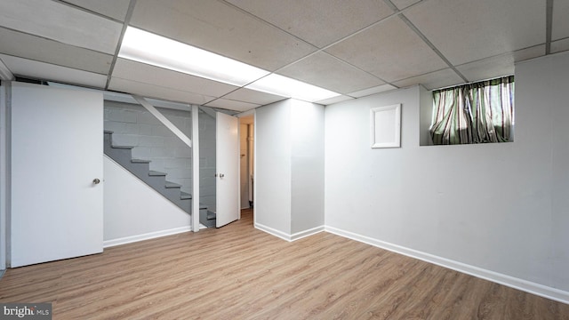 basement featuring a paneled ceiling and light wood-type flooring