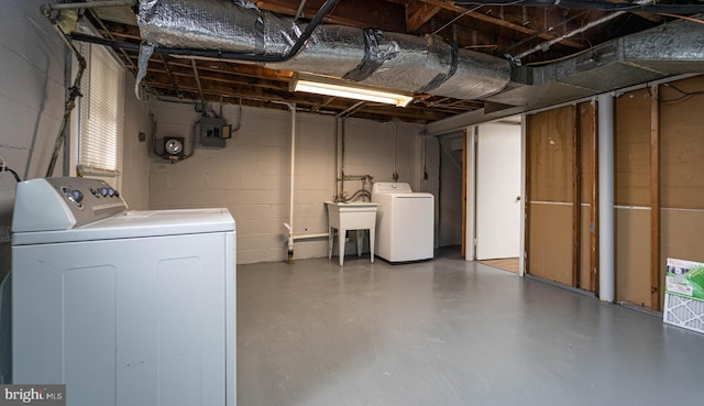 basement featuring electric panel, sink, and separate washer and dryer