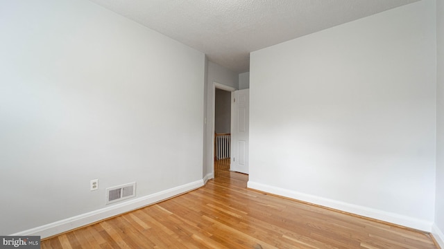 unfurnished room with a textured ceiling and light hardwood / wood-style floors