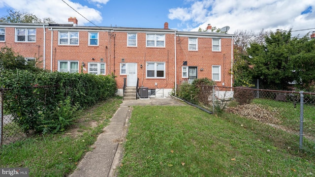 back of property featuring central AC unit and a lawn