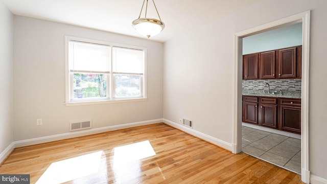 unfurnished dining area featuring sink and light hardwood / wood-style flooring