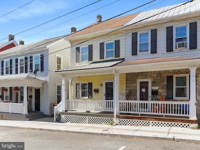 multi unit property with stone siding, a porch, and a chimney