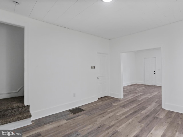 spare room with baseboards, wood finished floors, visible vents, and stairs