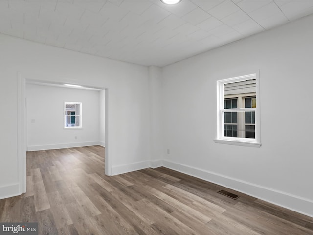 empty room with baseboards, wood finished floors, and visible vents