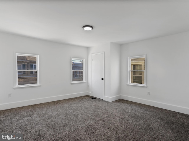 spare room featuring dark colored carpet